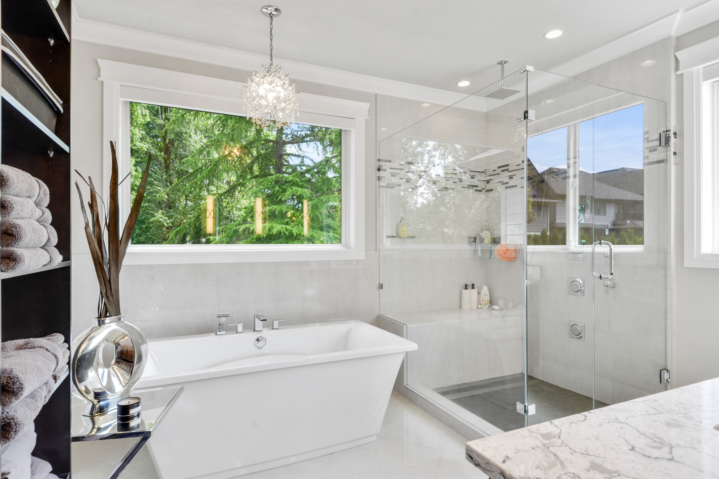Ensuite bathroom with freestanding tub, glass shower, and chandelier