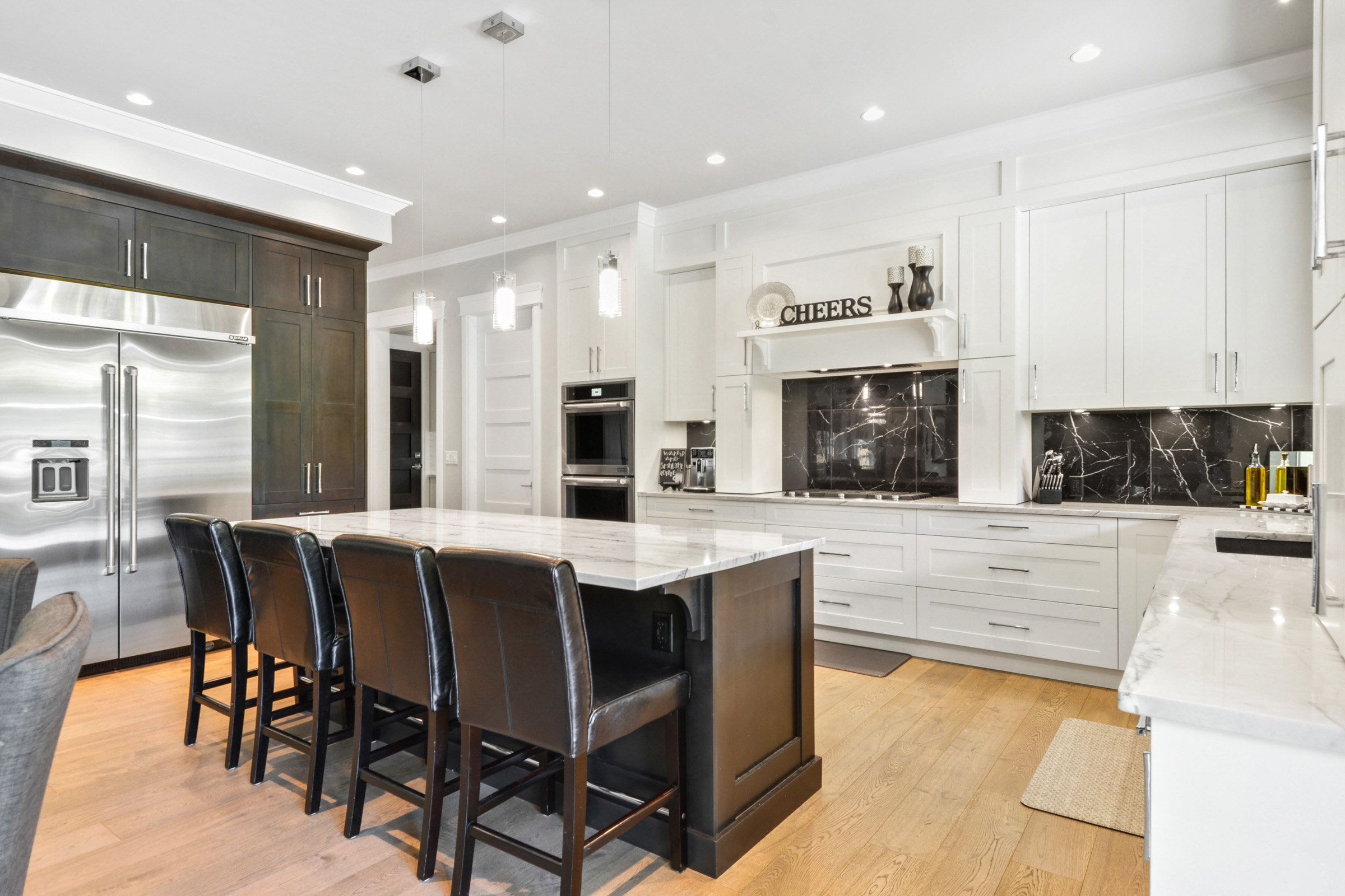 White shaker kitchen with marble island, espresso millwork, and black marble backsplash, renovated by Collins Interiors